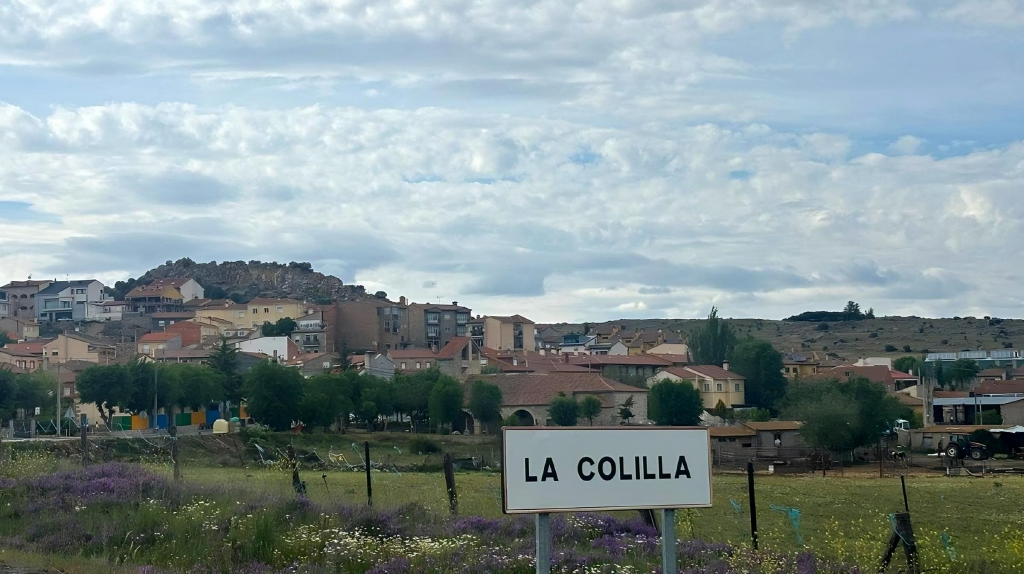 Cartel de entrada al pueblo de La Colilla con el fondo el pueblo