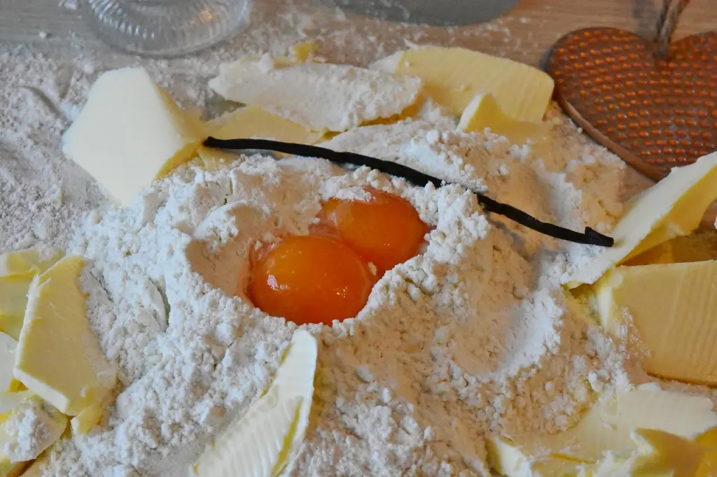 Ingredientes básicos y naturales como huevos frescos y harina sobre una mesa de cocina, preparados para elaborar postres tradicionales abulenses.